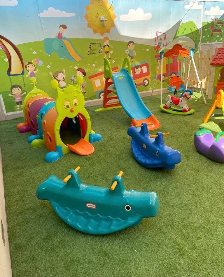 Area giochi interna con scivoli, dondolini e pareti decorate